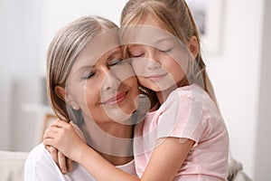 Happy grandmother hugging her granddaughter at home