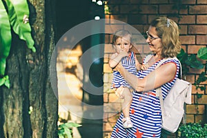 Happy grandmother lifting up her little granddaughter and hugging in garden at sunny day outdoors. Beautiful middle aged