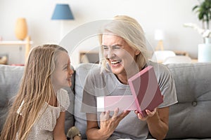 Happy grandmother opening gift box with present from grandchild