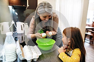 Happy grandmother showing chicken eggs to smiling granddaughter