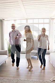 Happy grandparents and excited teenager girl dancing together, having fun