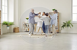 Happy grandparents and grandchildren spending time at home, dancing and having fun together