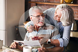 Happy grandparents having talks and laughs while eating at the kitchen
