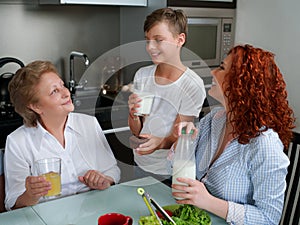Happy granny drinking juice with children in the kitchen