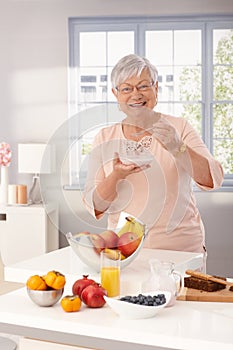 Happy granny eating breakfast cereal