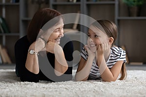 Happy granny and granddaughter kid resting together on heating floor