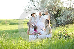 Happy granny hugging daughters and granddaughters, wearing white clothes outside.