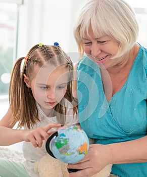 Happy granny showing globe to granddaughter