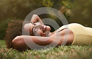 Happy, grass and portrait of black woman in park for relaxing, calm and peace in nature. Smile, garden and person laying