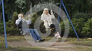 Happy gray-haired man with adult daughter swings on teeterboard