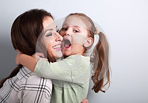 Happy grimacing kid wanting to biting her laughing mother in nos