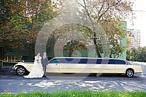 Happy groom and bride about long retro limousine