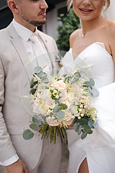 Happy groom and bride standing on terrace after first meeting. Handsome groom in light colour suit with his gorgeous