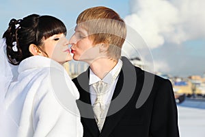 Happy groom and bride tender kiss at winter