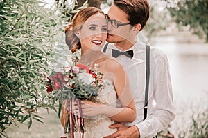 Happy groom kissing his bride in city Park