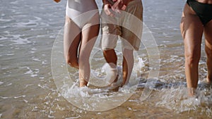 Happy group of barefoot men, women in swimwear at tropical trip come out of sea water, flirt, smile, chat. Cheerful