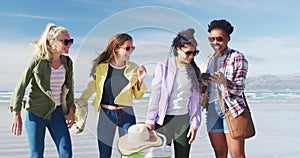 Happy group of diverse female friends having fun, taking selfie with smartphone at the beach