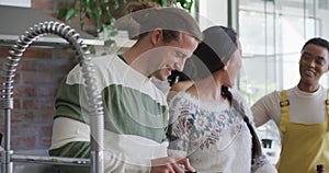 Happy group of diverse female and male friends cooking together in kitchen