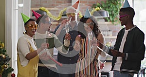 Happy group of diverse friends in party hats celebrating together, toasting with vine