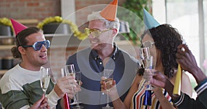 Happy group of diverse friends in party hats celebrating together, toasting with vine