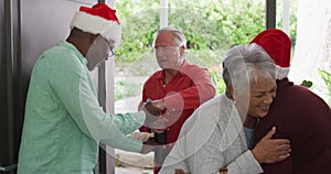 Happy group of diverse senior friends welcoming in doorway at christmas time