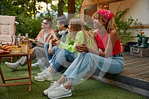 Happy group of friend sitting in row eating snacks rest during picnic