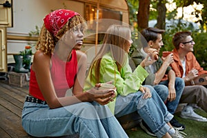 Happy group of friend sitting in row eating snacks rest during picnic