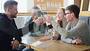 Happy group of friends or business colleagues drinking coffe and laughing and using computer together in a small cafe or