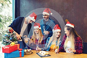 Happy group of friends celebrating Christmas drinking champagne and eating sweet food at dinner party