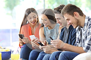 Happy group of friends checking smart phones