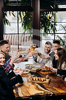 Happy group of friends drinking and clinking with beer and cocktails at brewery bar restaurant