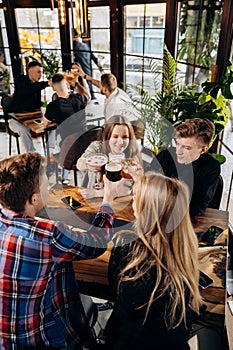 Happy group of friends drinking and clinking with beer and cocktails at brewery bar restaurant