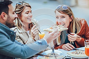 Group of friends eating pizza outdoors
