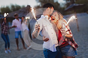 Happy group of friends lighting sparklers and enjoying freedom