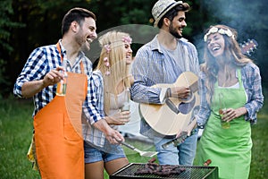 Happy group of friends making a barbecue together outdoors in the nature