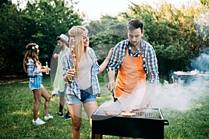 Happy group of friends making a barbecue together outdoors in the nature