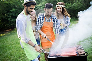 Happy group of friends making a barbecue together outdoors in the nature