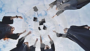 Happy group of graduated young students throwing hats.