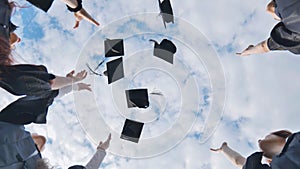 Happy group of graduated young students throwing hats.