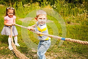 Happy group of kids playing tug of war in a park