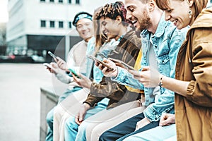 Happy group of multiracial teens using smart mobile phone outdoors - Diverse university students watching smartphones in college