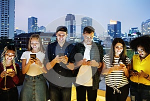 Happy group of young adults using smartphones in the cityscape