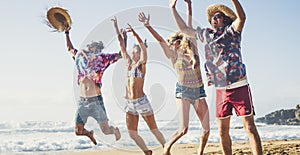 Happy group of young millennial active people jumping for fun at the beach on summer holiday vacation - travel and tourist concept