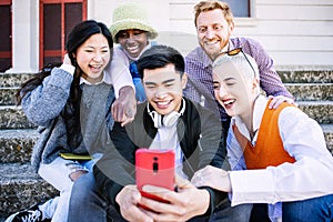 Happy group of young people having fun using mobile phone together outdoors