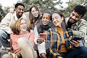 Happy group of young people having fun using smartphone outdoors