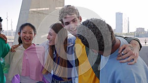 Happy group of young people hugging each other laughing outdoors.