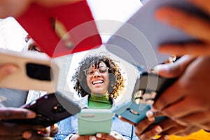 Happy group of young people using mobile phones outdoors.