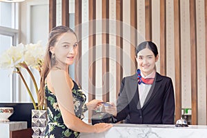 Happy guest and receptionist at hotel reception, Young travellers standing at reception desk with blurred female receptionist s