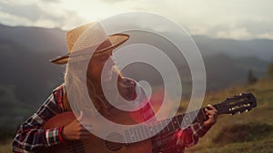 Happy guitarist smiling outdoors in mountains closeup. Joyful girl play guitar.