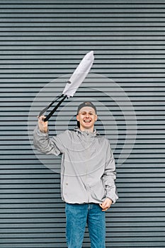 Happy guy in casual clothes waving eco bag in hands on gray wall background, looking into camera with smile on face. Vertical. Eco